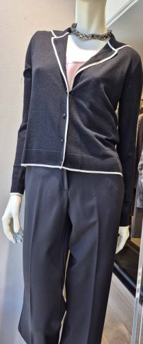 Doudoune sans manches blanche avec capuche noire, associée à un pull rose chiné et un pantalon noir.