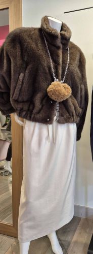 Look féminin élégant avec veste marron effet fourrure, jupe longue écrue et accessoire en chaîne.