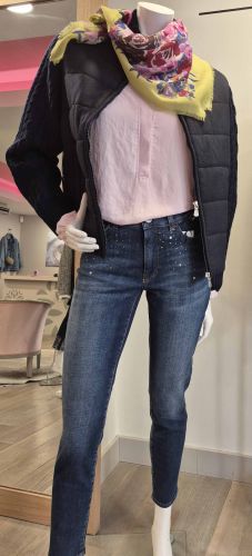 Doudoune sans manches blanche avec capuche noire, associée à un pull rose chiné et un pantalon noir.